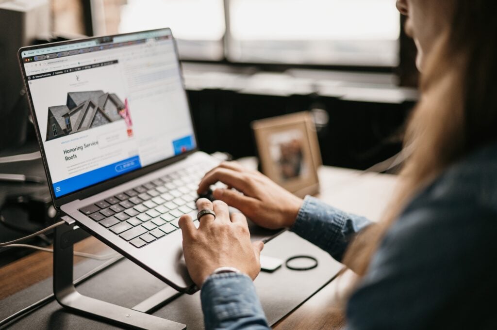 Professional working at a desk on Hook Agency’s site, optimizing content quality. House image, frame, and window in background.