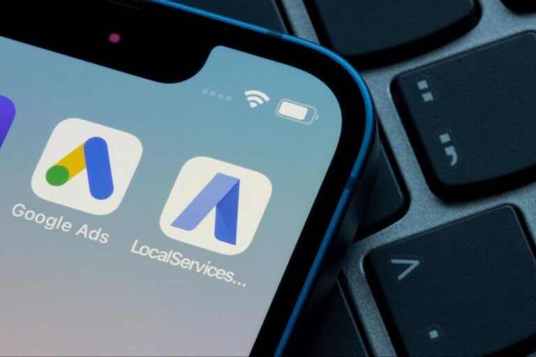A smartphone displays Google Ads for Contractors and LSAs app icons, positioned on a black keyboard—Hook Agency digital tools in focus.