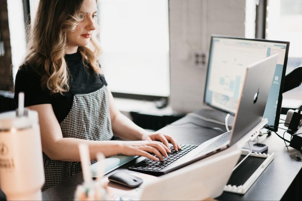 SEO specialist with wavy blonde hair monitors traffic and analytics on a laptop in Hook Agency’s bright, modern office.
