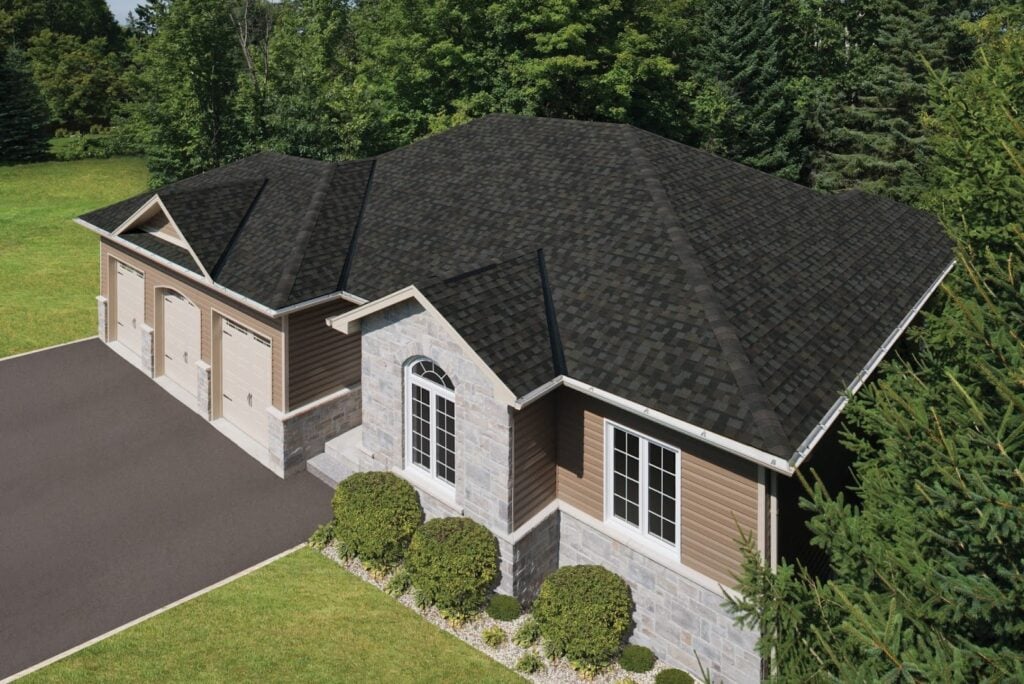 Aerial view of a single-story home featuring IKO Shingles 2025 roof, stone and wood exterior, three-car garage, and landscaped yard.