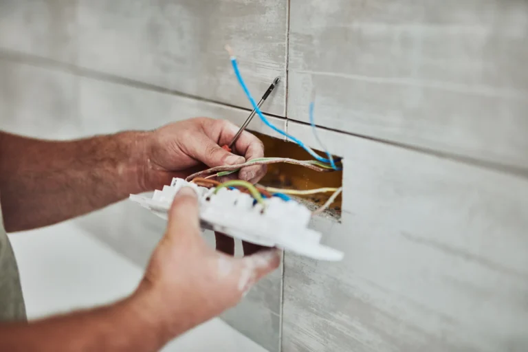 An electrician expertly installs a light switch, precisely connecting wires with a screwdriver. This seamless execution demonstrates superior craftsmanship—a prime example of exceptional electrician marketing at Hook Agency.