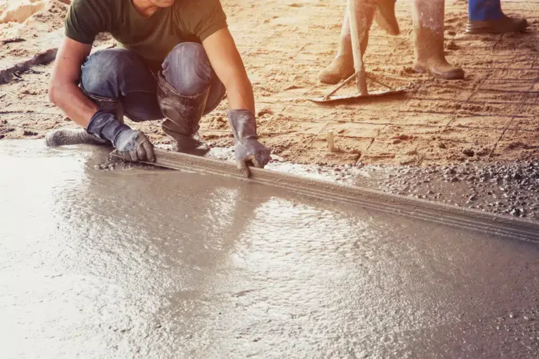 On Hook Agency's website: 

A skilled worker in gloves expertly smooths wet concrete for a hardscaping project, with sunlight accentuating the precision of the task. Nearby, an assistant is poised with a rake, ready to contribute to the refined pavement work.