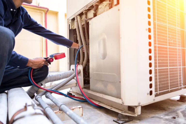 An HVAC technician expertly repairs an industrial air conditioning unit on a rooftop, utilizing gauges and tools with precision. Sunlight gleams off the metal casing, highlighting the network of pipes in the foreground.