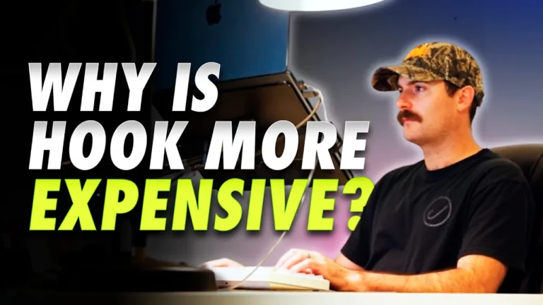 Man in camo hat and black shirt types at computer; text over image reads "WHY IS HOOK PRICING MORE EXPENSIVE?" Lamp above.
